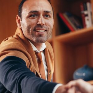 man smiles and reaches out hand to shake someone's hand